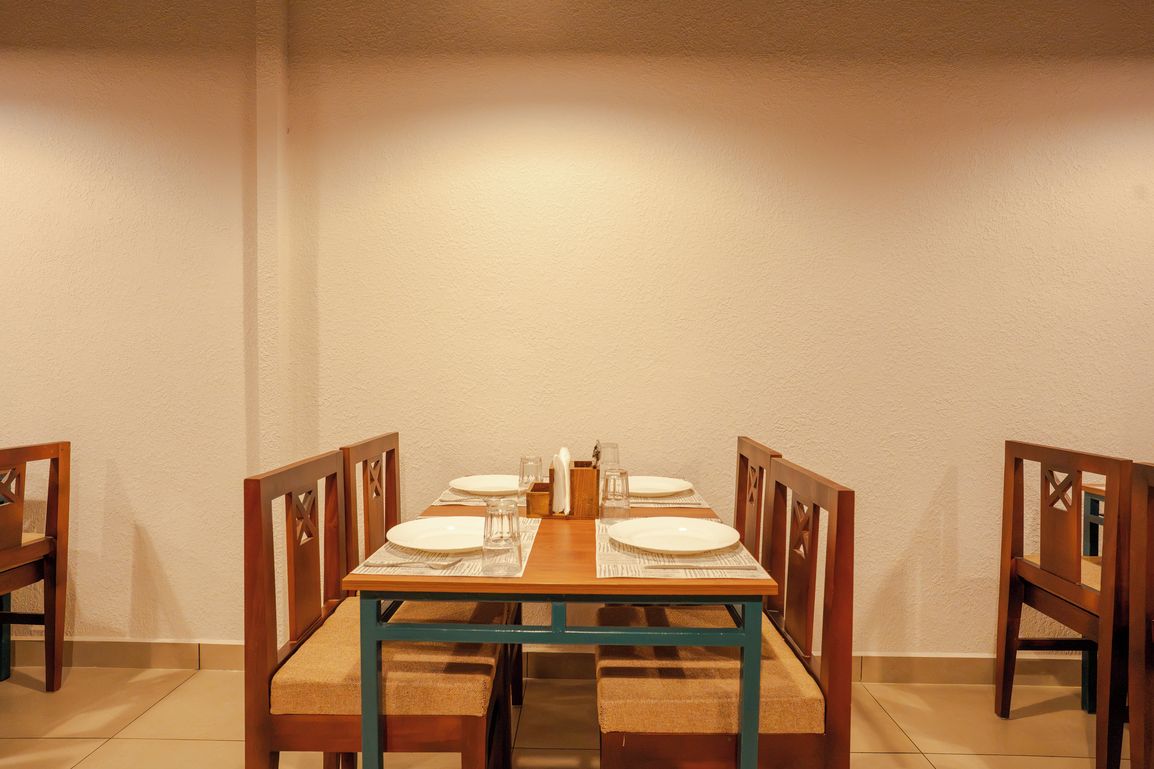 A dining table set for four with chairs, a vase, and a salt and pepper shaker.