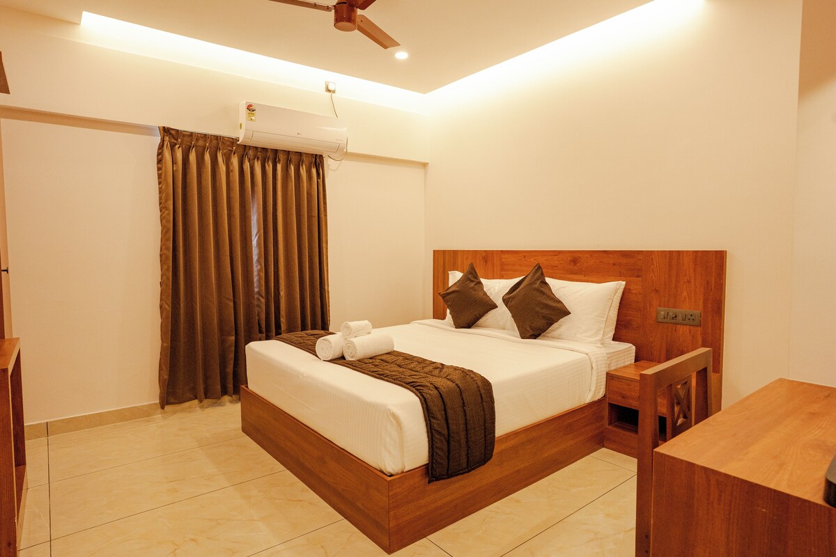 A hotel room with a bed, a nightstand, a wooden headboard, a ceiling fan, and a window with curtains.