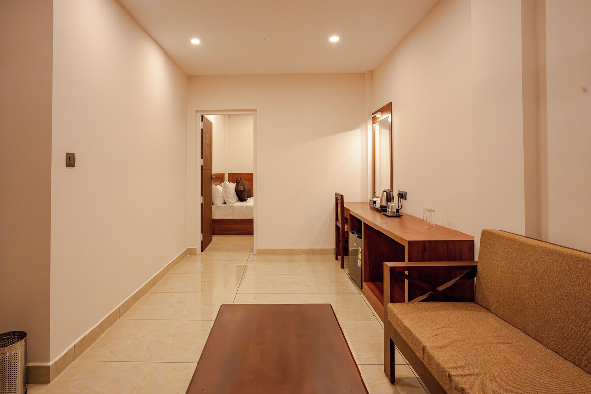 A hotel hallway with a wooden bench, a small table, and a mirror on the wall.