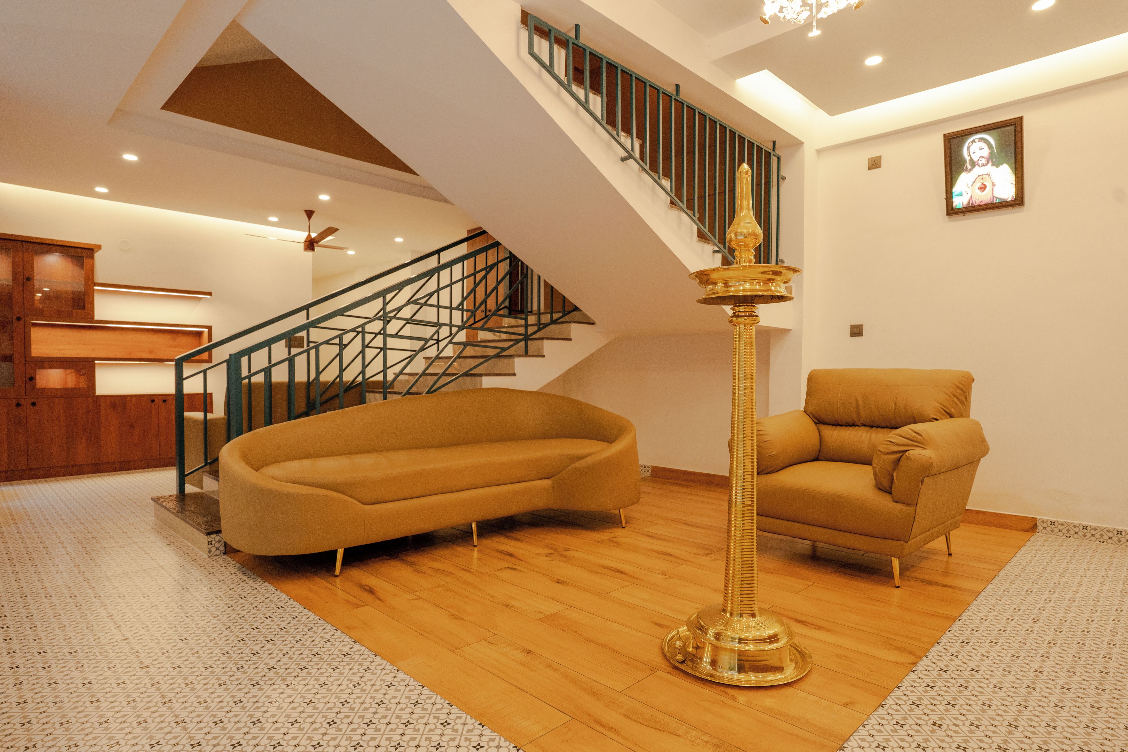 Un amplio salón con un sofá curvo, una lámpara de pie alta y una escalera.