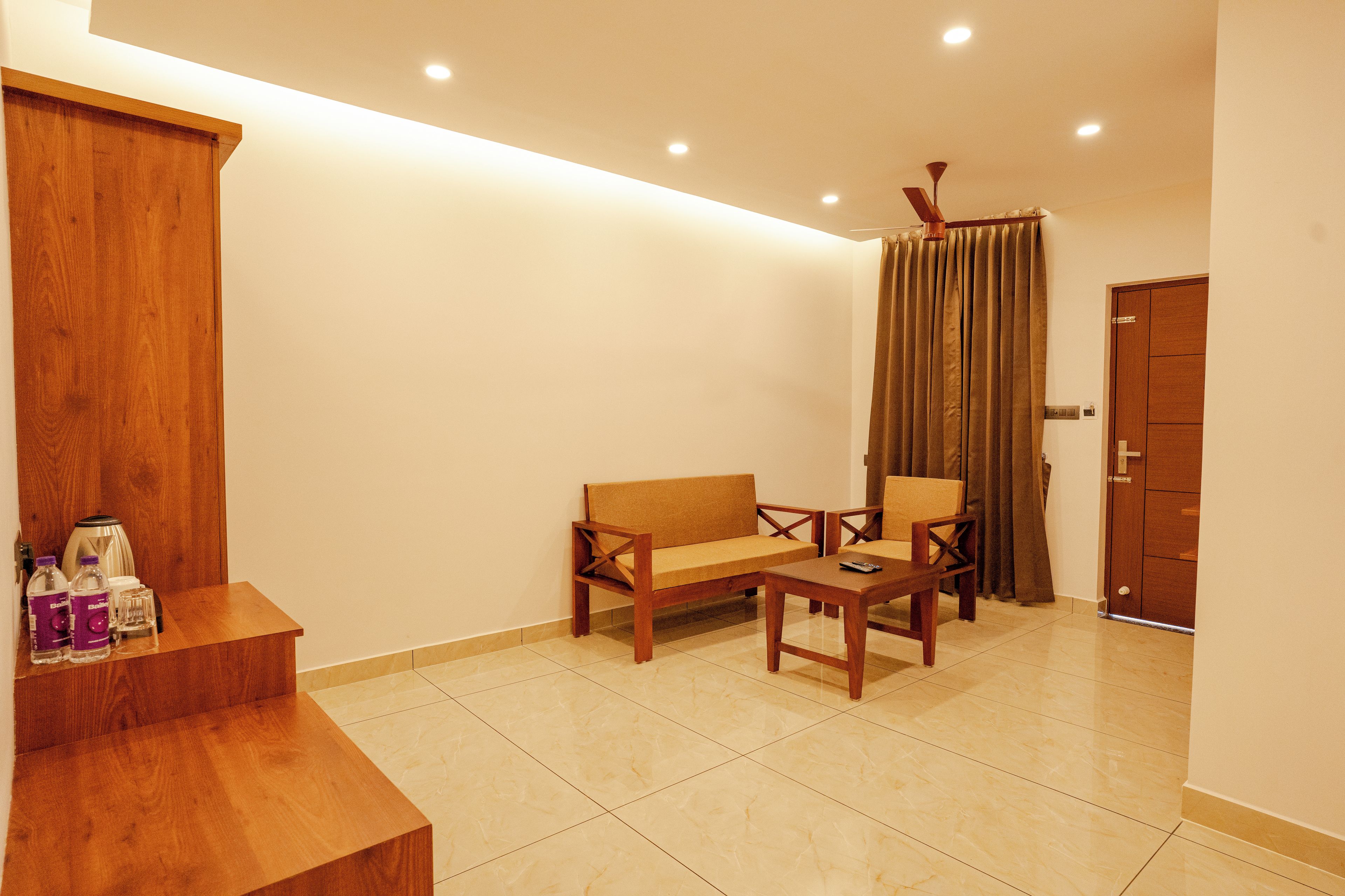 Una habitación con sofá, sillón, mesa de centro y un armario de madera.