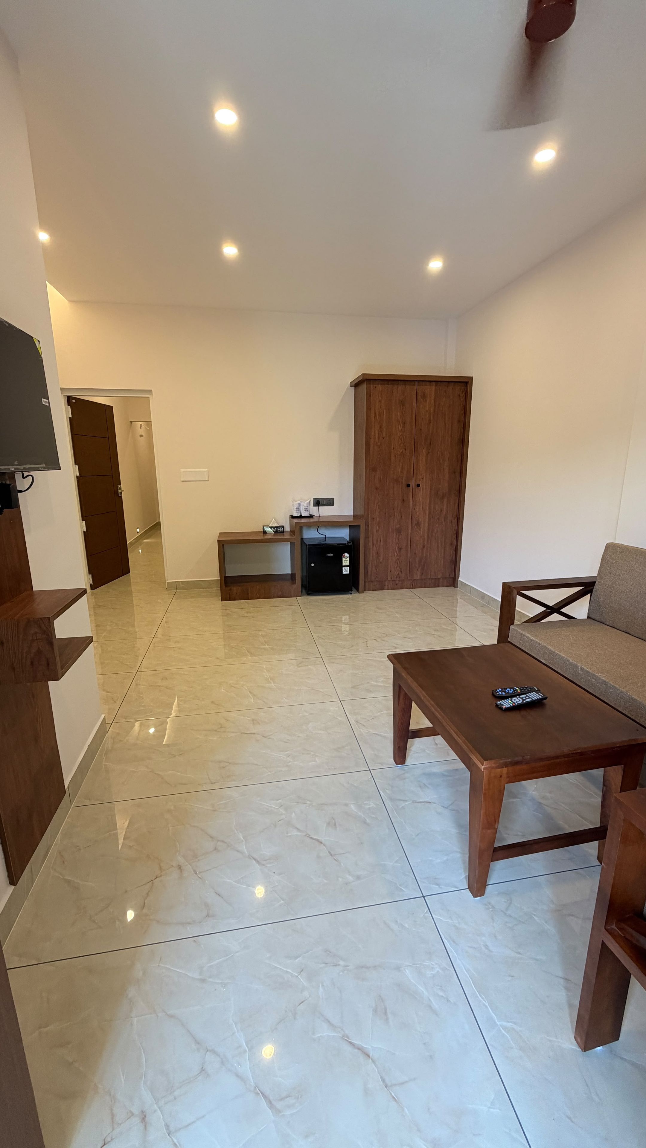 A spacious living area with a flat-screen TV, a wooden cabinet, a sofa, and a coffee table.