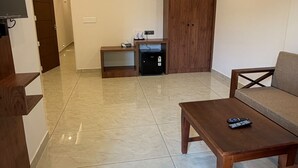 A spacious living area with a flat-screen TV, a wooden cabinet, a sofa, and a coffee table.