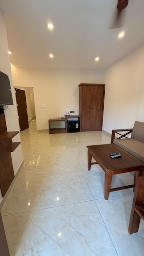 Un salón amplio con una televisión de pantalla plana, un mueble de madera, un sofá y una mesa de centro.