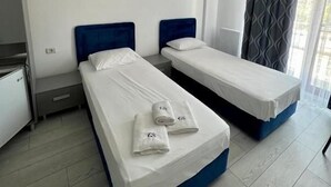 A hotel room with two single beds, a kitchenette, and a large window with curtains. - Luxury by Saray (Eforie Nord)