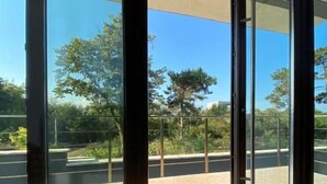 A hotel lobby with a large glass door leading to a balcony, a tufted chair, and a sign indicating an exit. - Luxury by Saray (Eforie Nord)