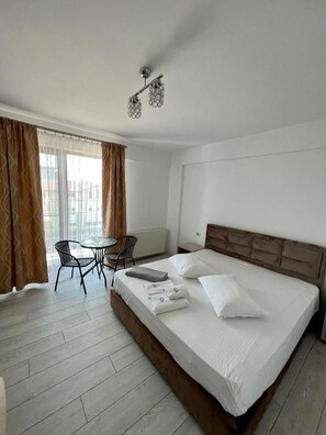 A hotel room with a large bed, a round table, and a chair. - Luxury by Saray (Eforie Nord)