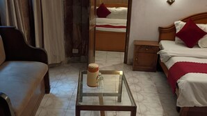 A hotel room with a bed, a sofa, a glass-top table with a mug, and a nightstand. - HOTEL FILIGREE THE MALL MUSSOORIE (Mussoorie)