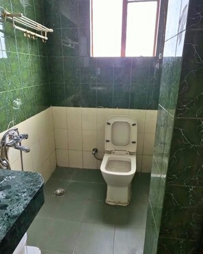 Uma casa de banho com sanita, chuveiro e lavatório.