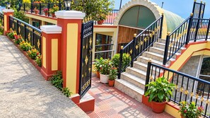 Um edifício com escadaria, portão e vasos de plantas.