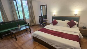 A hotel room with a bed, a green sofa, a wooden table, a chair, and a mirror. - HOTEL FILIGREE THE MALL MUSSOORIE (Mussoorie)