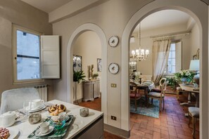 A dining area with a table set for a meal, a kitchen area with a radiator, and a hallway leading to another room. - Modern Apartment With Terrace, Lucca (Lucca)