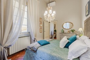 A bedroom with a bed, a chandelier, a mirror, and a radiator. - Modern Apartment With Terrace, Lucca (Lucca)