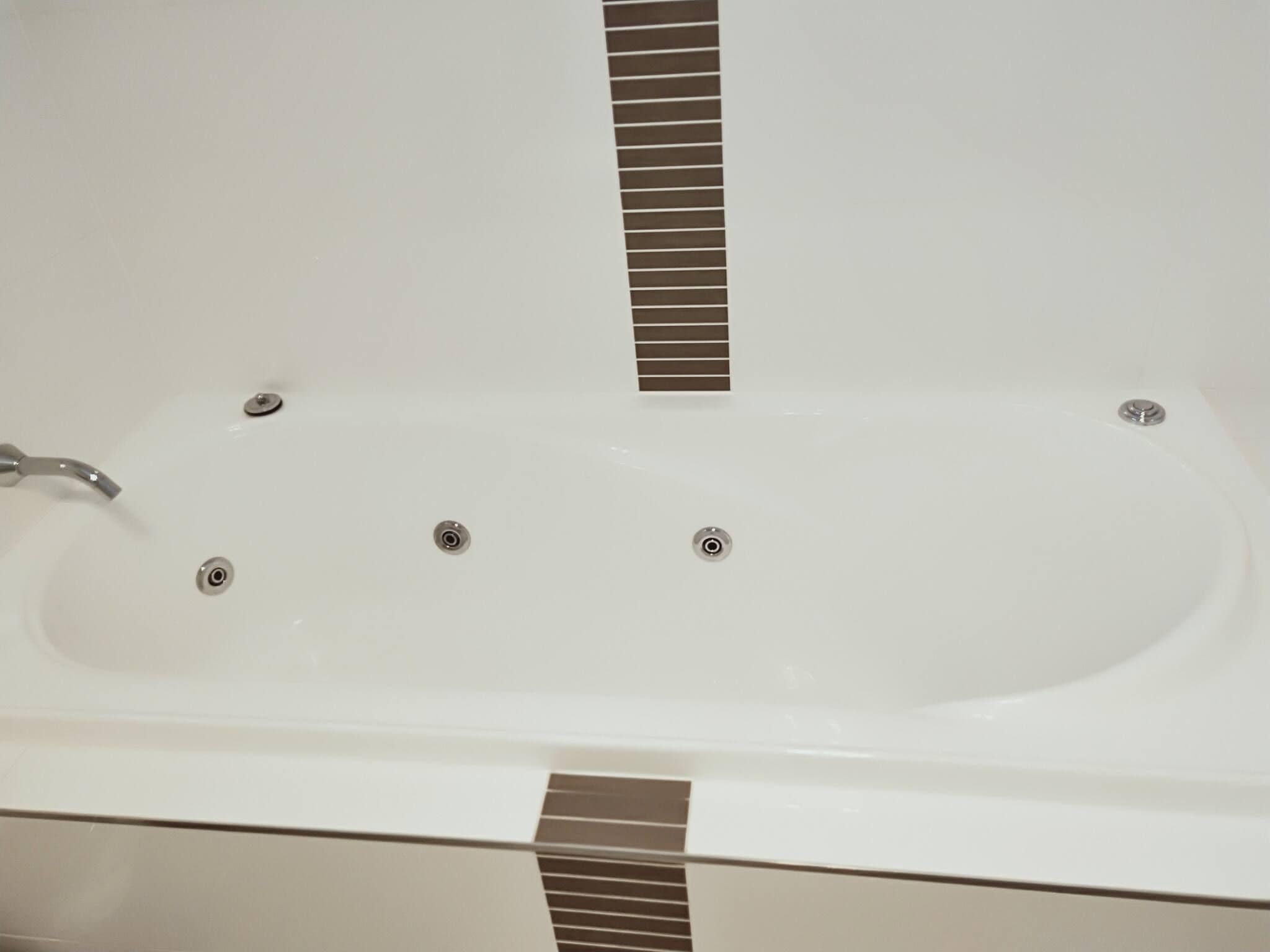 A white bathtub with a single faucet and three drain holes.