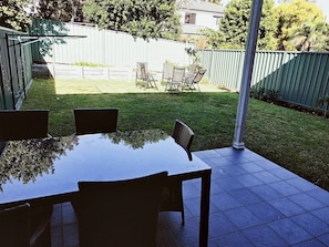 An outdoor patio with a table and chairs, a covered seating area, and a fenced yard.