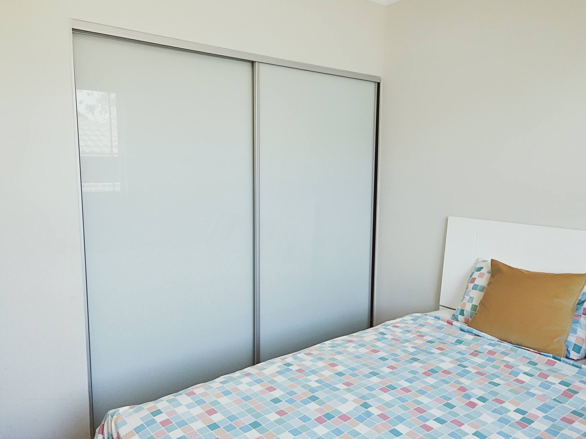 Ein Schlafzimmer mit einem Bett, einem Kopfteil, einem Kissen und einem Kleiderschrank.