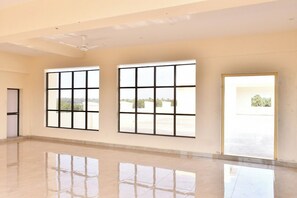 A spacious room with large windows, a ceiling fan, and a reflective floor.