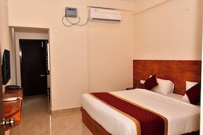 Ein Hotelzimmer mit Bett, Fernseher, Schreibtisch und Klimaanlage.
