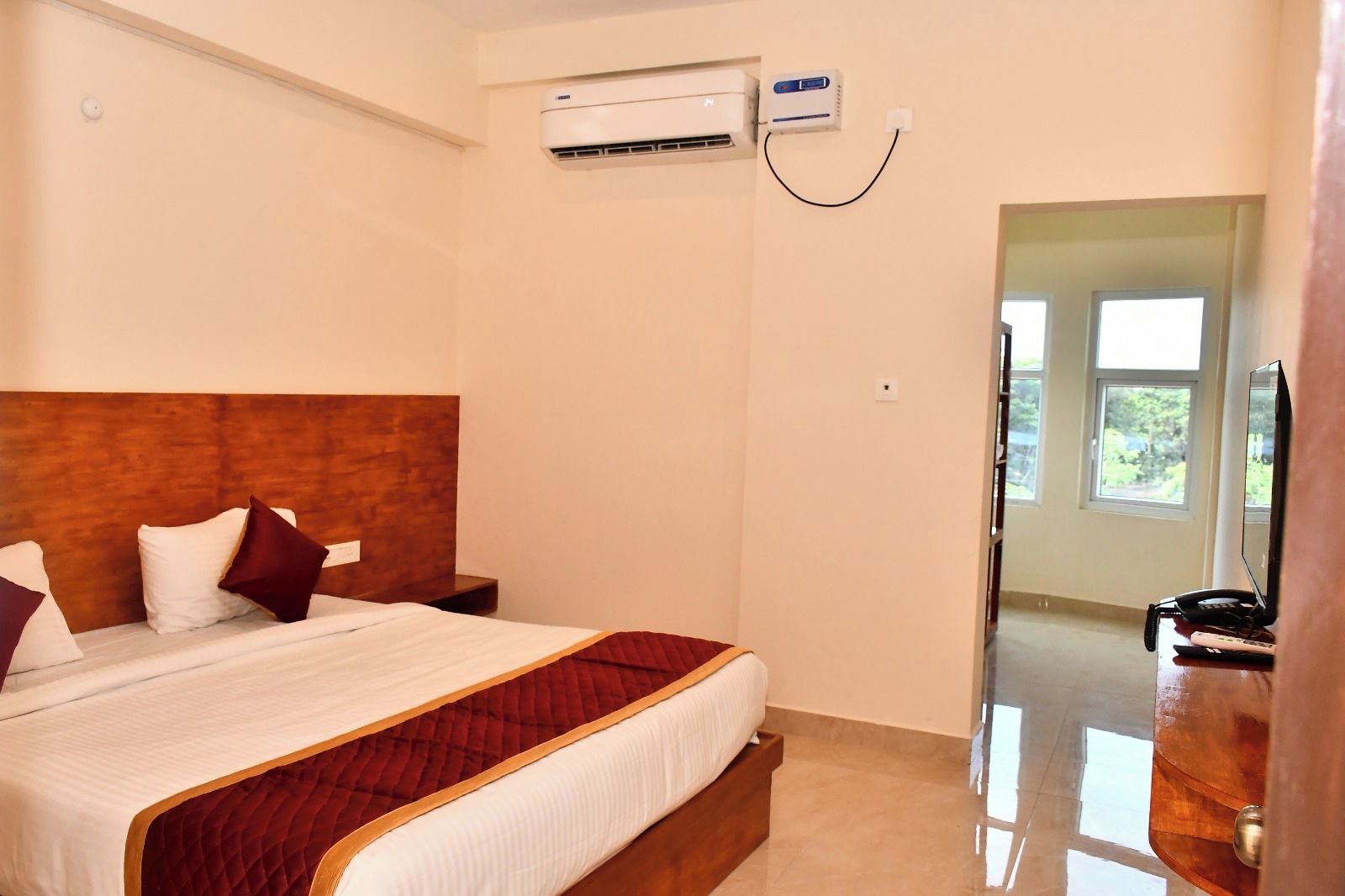 Una habitación de hotel con cama, mesita de noche, aire acondicionado y vistas al exterior.