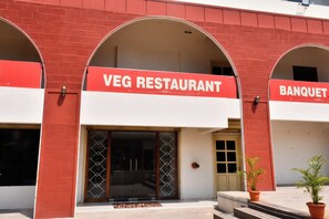 A building with a red and white facade, featuring a sign for a 'VEG RESTAURANT' and a 'BANQUET'. - Grami Cafe (Puducherry)