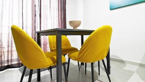 A dining area with a round table and four yellow chairs. - White tulip apartment (Safi)