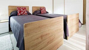 A modern bedroom with two wooden beds, a nightstand, and a large wardrobe. - White tulip apartment (Safi)