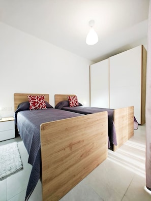 A modern bedroom with two wooden beds, a nightstand, and a large wardrobe. - White tulip apartment (Safi)