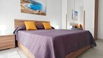 Een moderne slaapkamer met een groot bed, een nachtkastje, een bedtafel en een wandlamp.