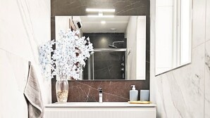 A bathroom with a white vanity, a mirror, a towel rack, a flower vase, and a toilet. - White tulip apartment (Safi)