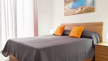 Una camera da letto con un letto, cuscini, un comodino, un tappeto e un quadro appeso al muro.
