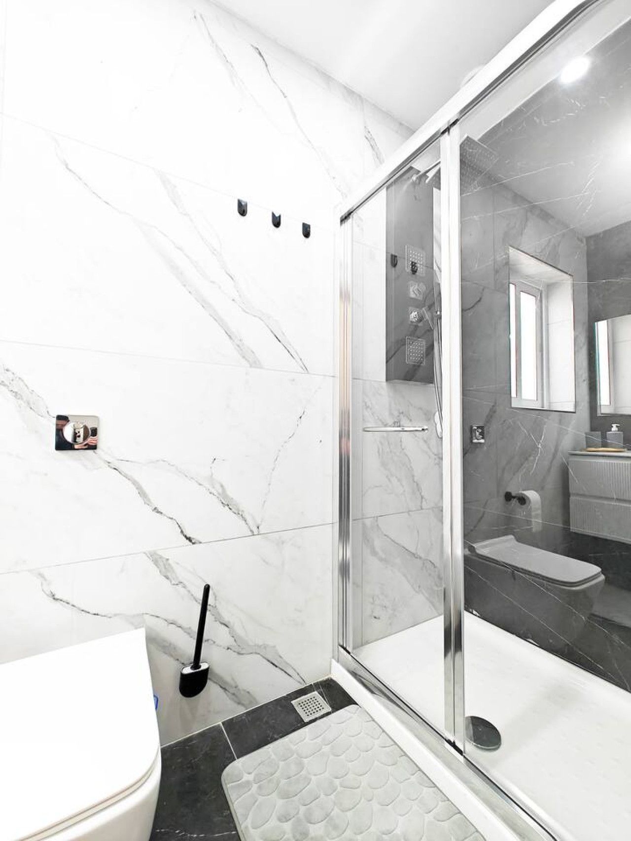 Une salle de bain moderne avec une douche à parois de verre, des toilettes et un lavabo avec un miroir.
