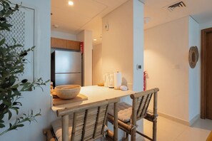 A modern kitchen with a wooden table, chairs, and a refrigerator. - Vanilla Homes Modern 1BR in Reem Island (Abu Dhabi)