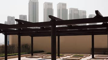 Área de piscina no terraço com estrutura de pérgola, cercada por um horizonte urbano de arranha-céus.