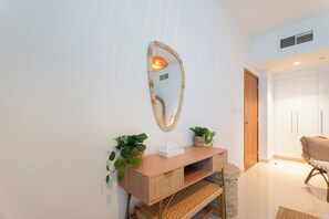 A modern interior with a wooden console table, wicker baskets, a mirror, and a chair.