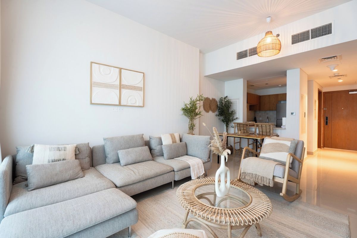 Uma sala de estar moderna com um sofá seccional, uma mesa de centro redonda e um espaço de jantar com cadeiras.