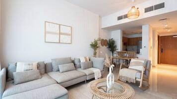 Uma sala de estar moderna com um sofá seccional, uma mesa de centro redonda e um espaço de jantar com cadeiras.