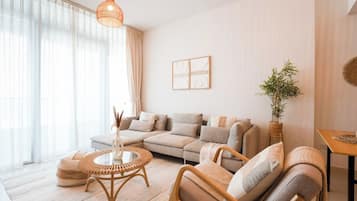 A modern living room with a sectional sofa, a round coffee table, and a hanging light fixture.