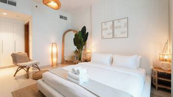 A hotel room with a large bed, a chair, a bedside table with a lamp, and a mirror.
