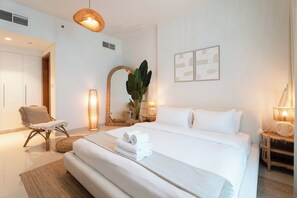 A hotel room with a large bed, a chair, a bedside table with a lamp, and a mirror. - Vanilla Homes Modern 1BR in Reem Island (Abu Dhabi)