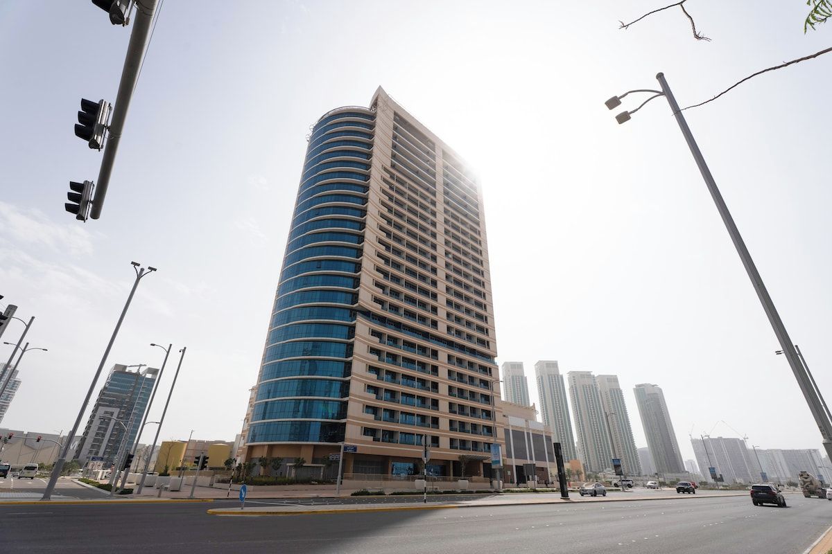 A tall, modern building with a curved facade, multiple floors, and a flat roof.
