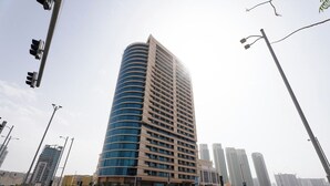 Um edifício alto e moderno com fachada curva, vários andares e telhado plano.