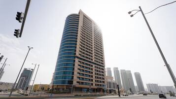 A tall, modern building with a curved facade, multiple floors, and a flat roof.