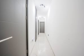 Un pasillo estrecho y bien iluminado con una puerta al final, que da a una habitación.