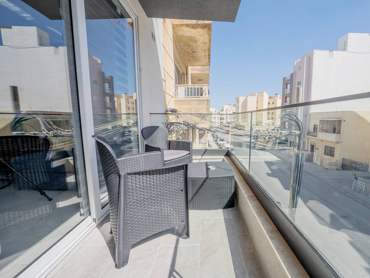 Een balkon met rieten meubilair en een helder uitzicht op de skyline.