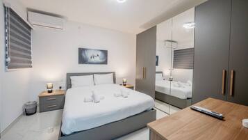 A modern bedroom with a bed, bedside tables, a mirror, and a wooden desk.