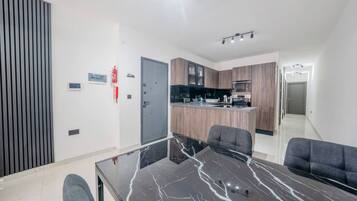 A modern kitchen with wooden cabinets, a central island, and a dining area with a glass table and chairs.