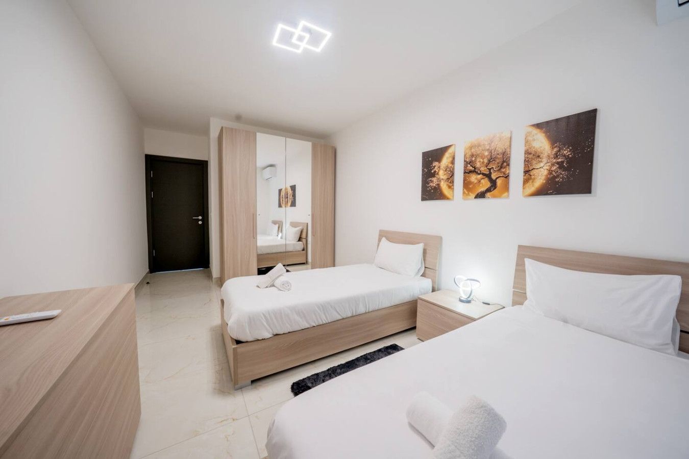 Een hotelkamer met twee bedden, een kledingkast, een nachtkastje en kunst aan de muur.
