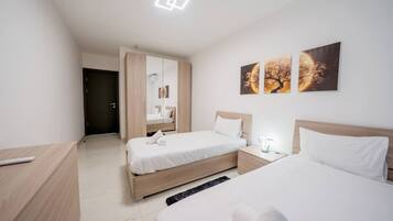 Een hotelkamer met twee bedden, een kledingkast, een nachtkastje en kunst aan de muur.