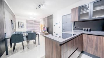 A modern kitchen with a central island, built-in cabinets, and a dining area with chairs.