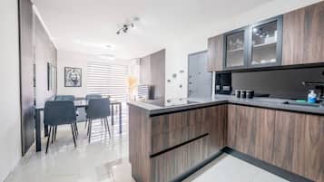 A modern kitchen with a central island, built-in cabinets, and a dining area with chairs.